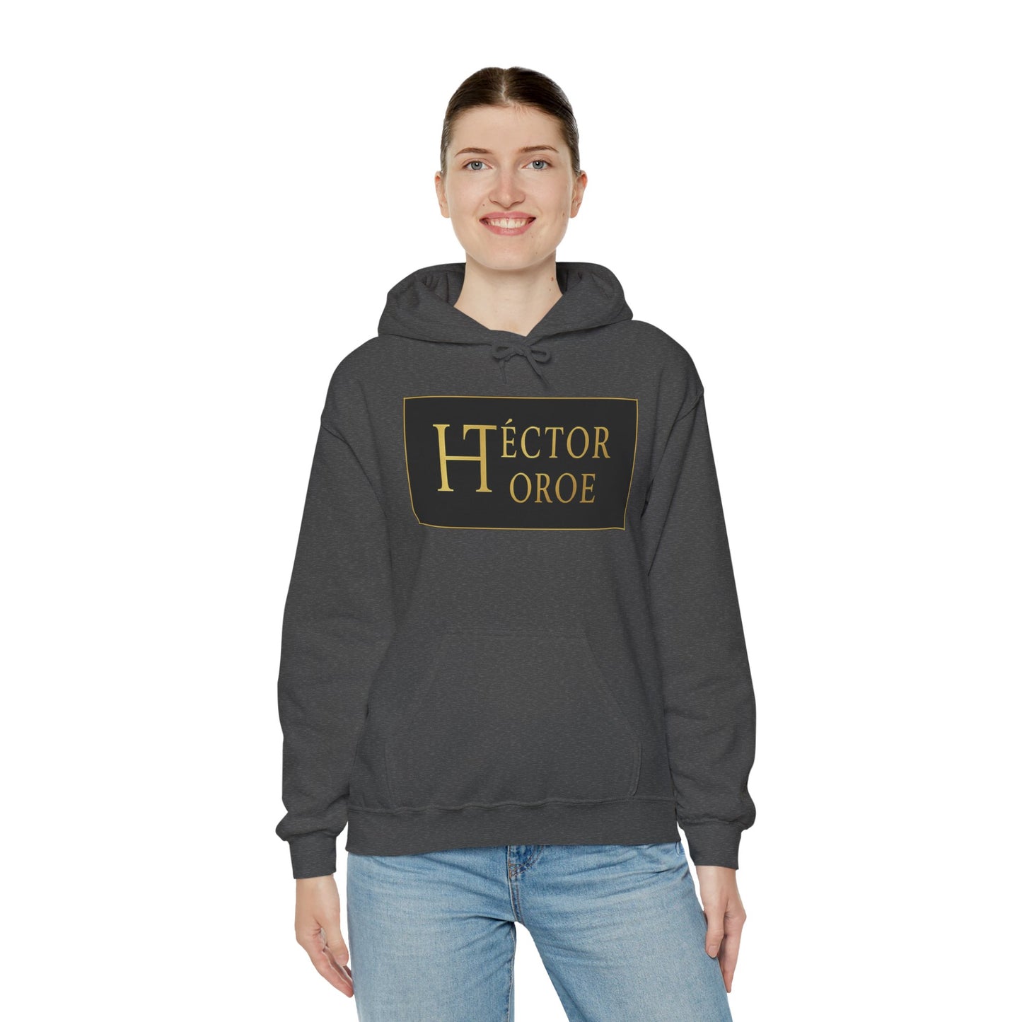 una mujer con sudadera brezo oscuro con capucha y bolsillo frontal, con un logotipo rectangular negro y dorado en el centro que muestra el texto “Héctor Toroe”.