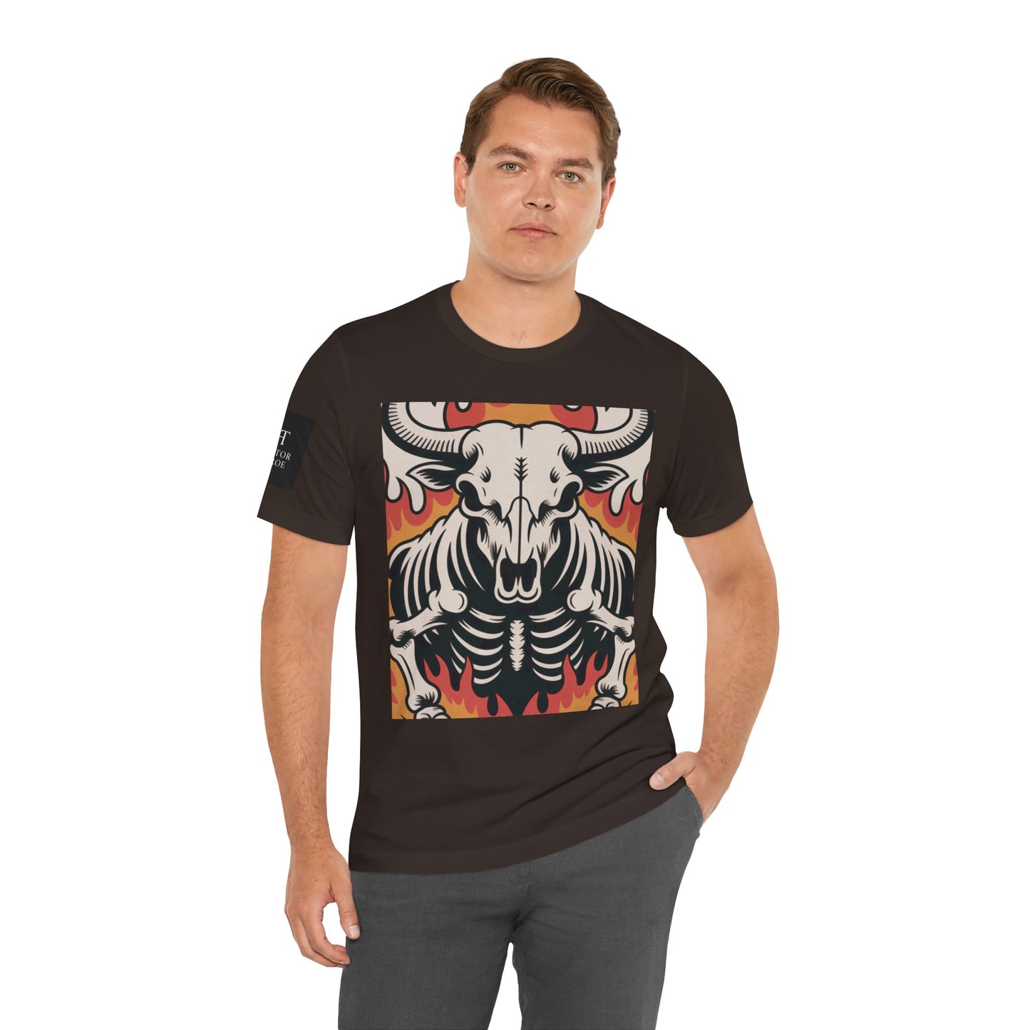 Hombre usando una camiseta cafe de manga corta con un diseño gráfico central de una calavera de toro con cuernos, estilo ilustración, sobre un fondo de llamas en tonos rojo, naranja y negro.
