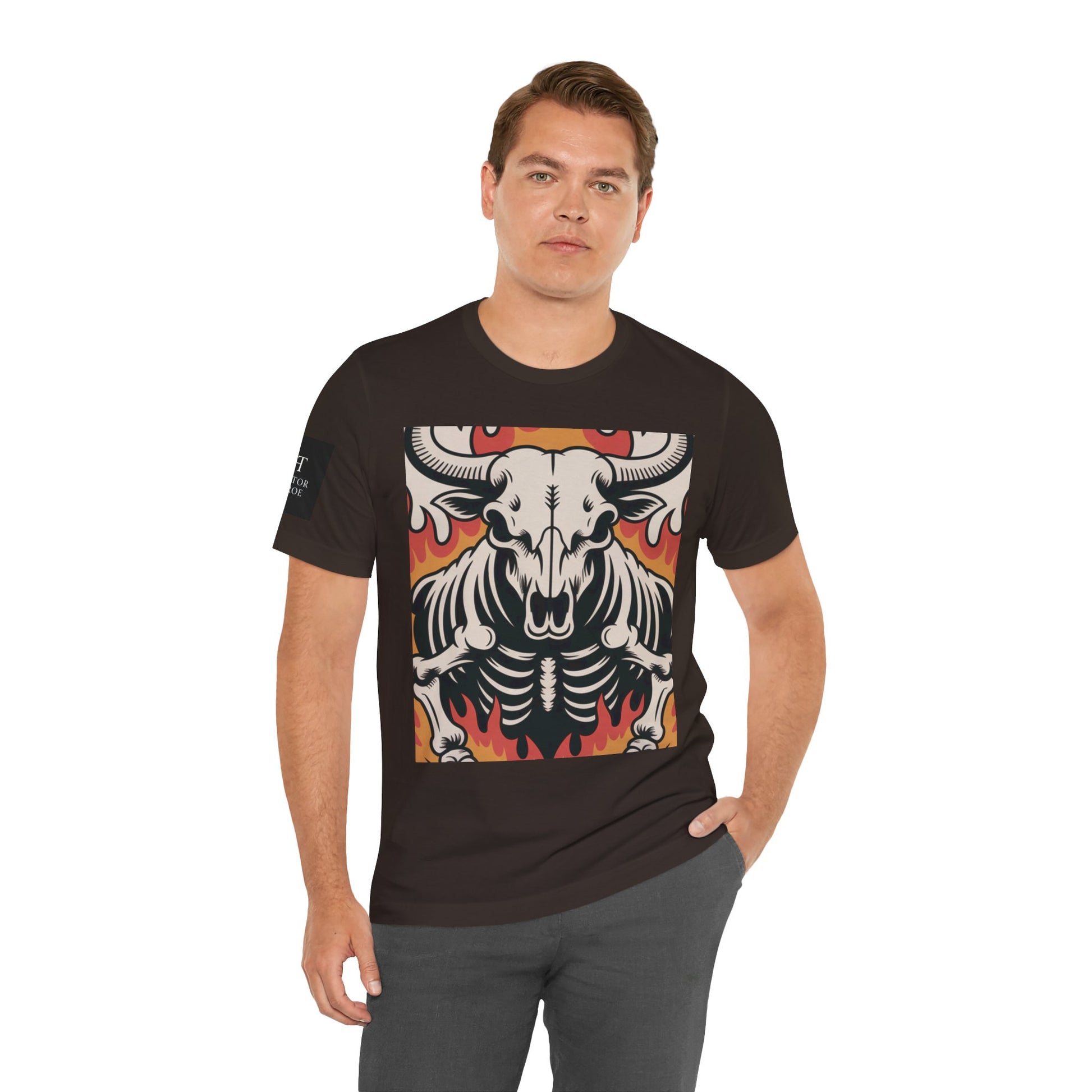 Hombre usando una camiseta cafe de manga corta con un diseño gráfico central de una calavera de toro con cuernos, estilo ilustración, sobre un fondo de llamas en tonos rojo, naranja y negro.