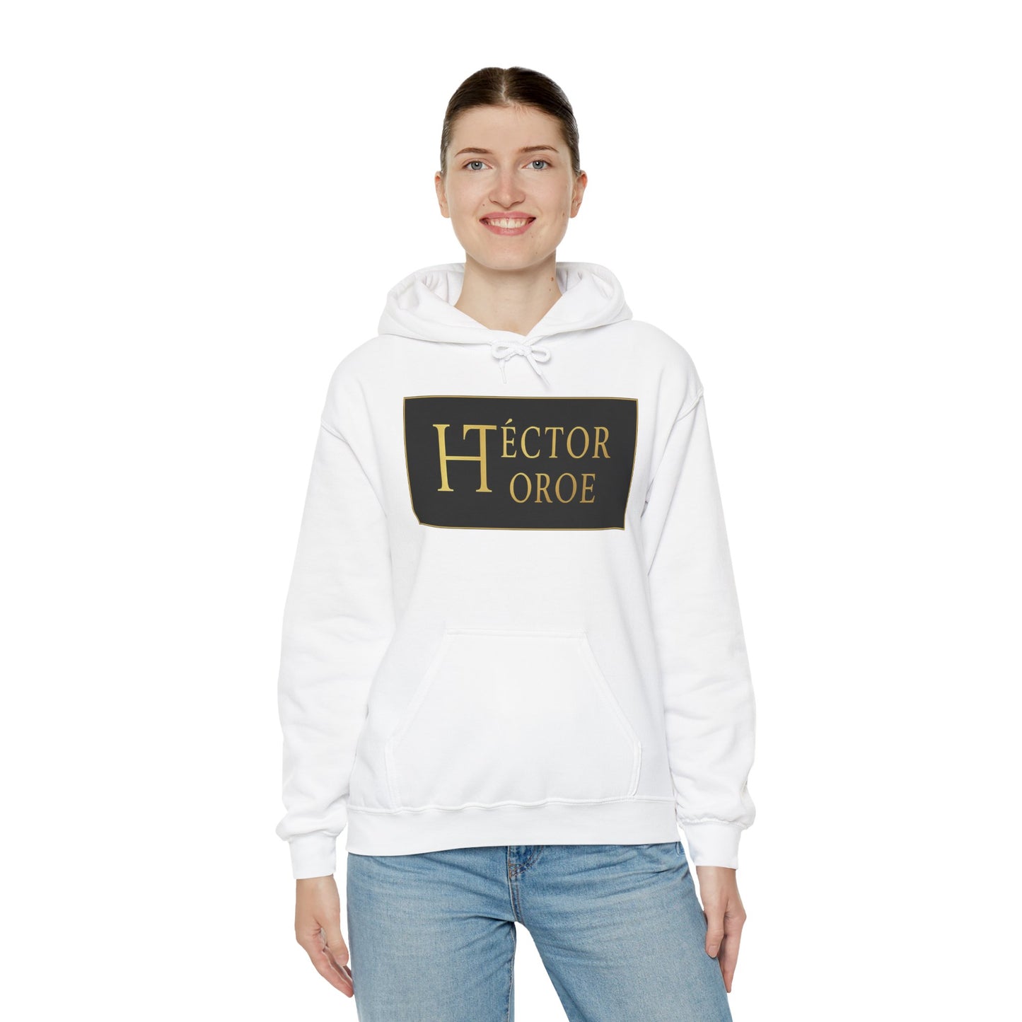 una mujer con sudadera blanca con capucha y bolsillo frontal, con un logotipo rectangular negro y dorado en el centro que muestra el texto “Héctor Toroe”. 