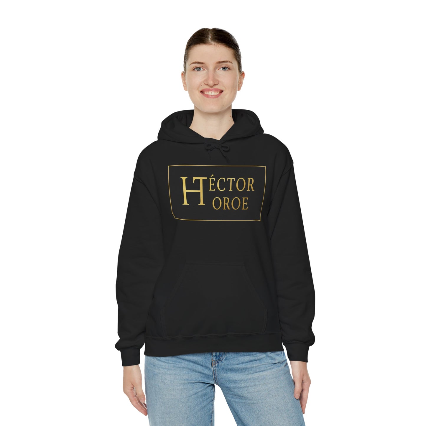 una mujer con sudadera negro con capucha y bolsillo frontal, con un logotipo rectangular negro y dorado en el centro que muestra el texto “Héctor Toroe”. 