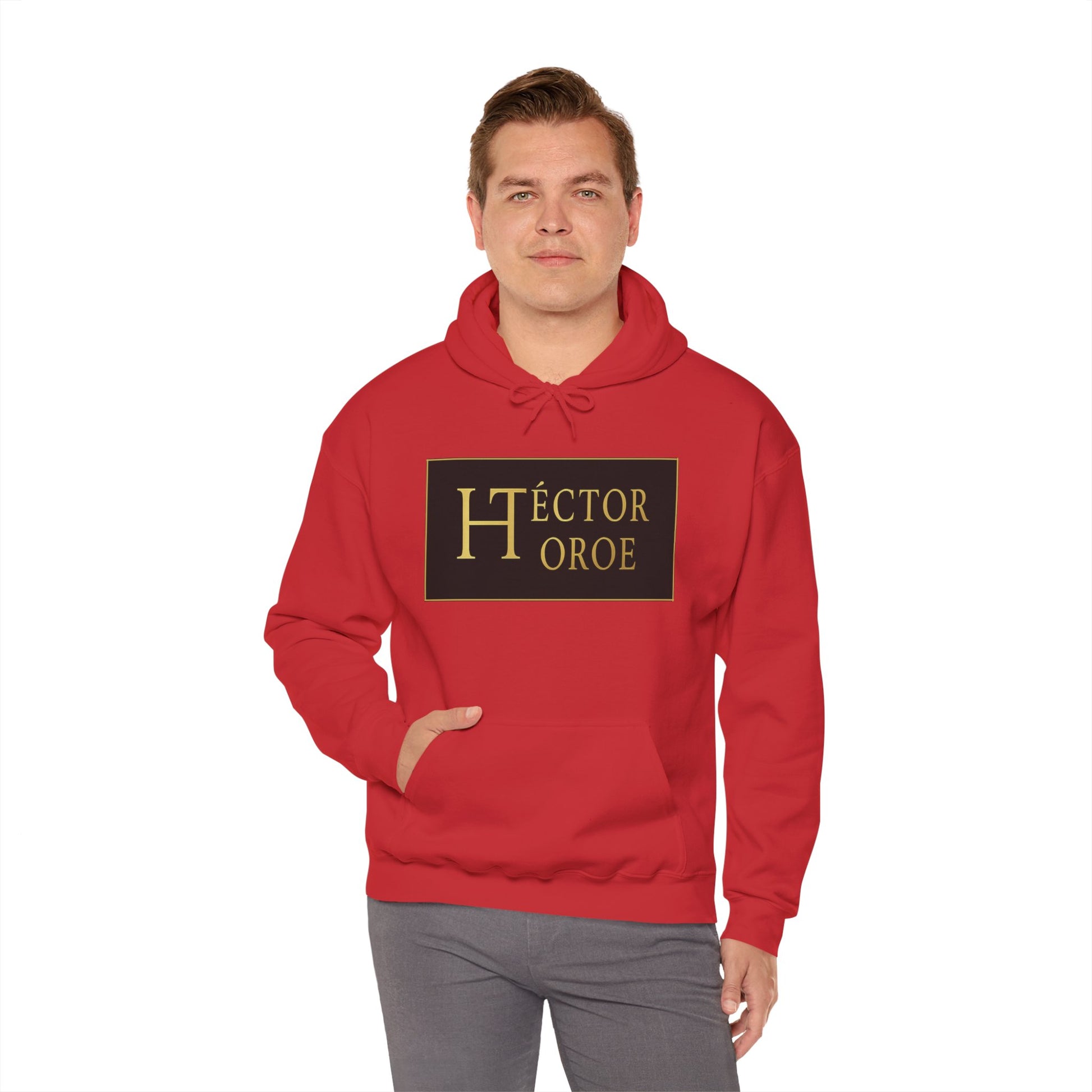 un hombre con sudadera rojo con capucha y bolsillo frontal, con un logotipo rectangular negro y dorado en el centro que muestra el texto “Héctor Toroe”.