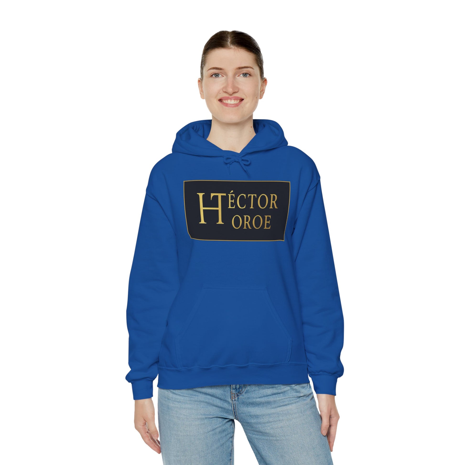 una mujer con sudadera royal con capucha y bolsillo frontal, con un logotipo rectangular negro y dorado en el centro que muestra el texto “Héctor Toroe”. 