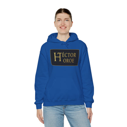 una mujer con sudadera royal con capucha y bolsillo frontal, con un logotipo rectangular negro y dorado en el centro que muestra el texto “Héctor Toroe”. 